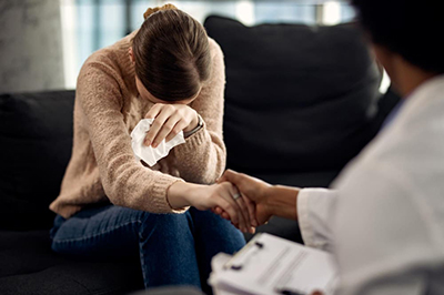 Person holding a therapist's hand while expressing emotion during a counseling appointment